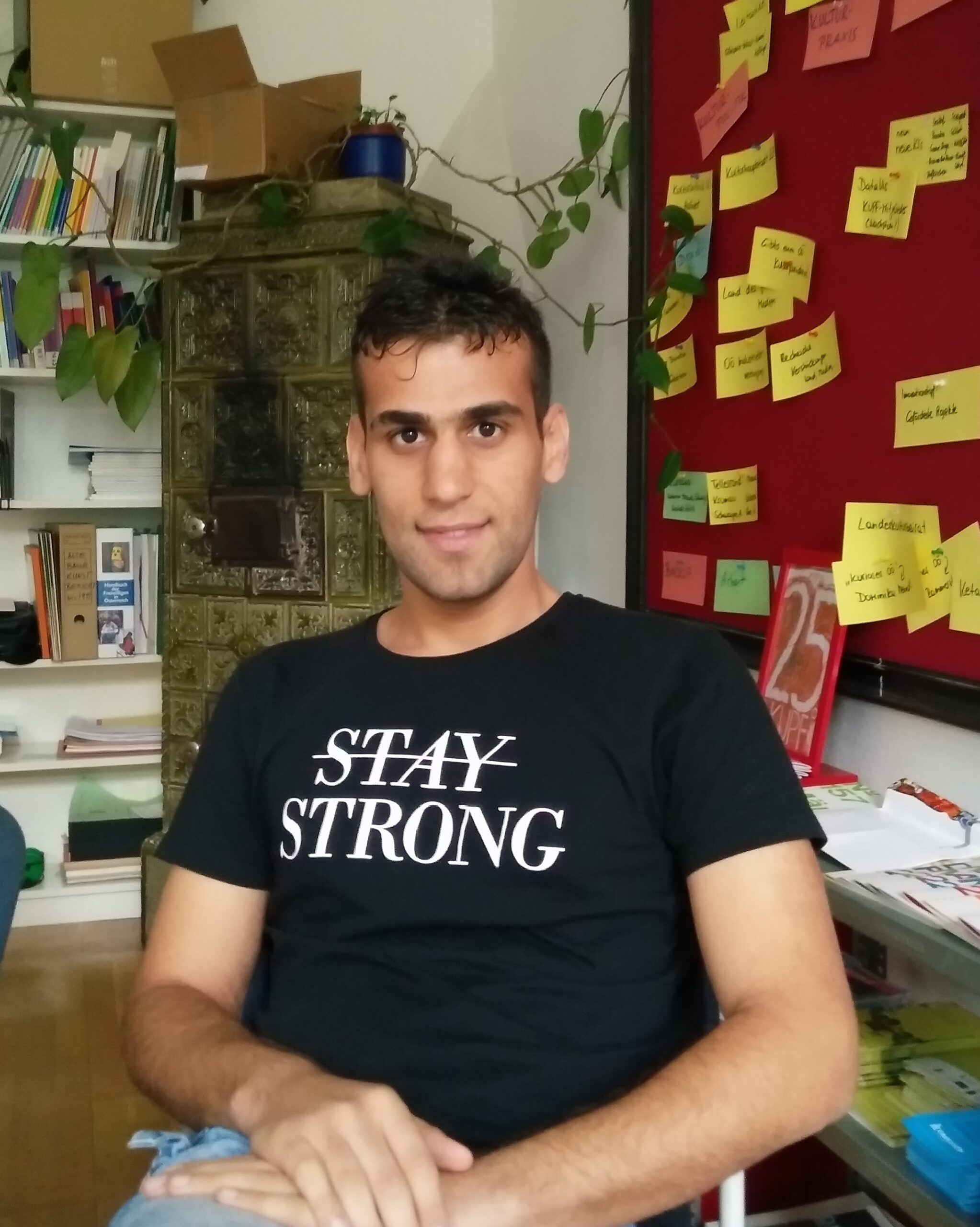 Ahmed Alqaysi zu Gast im KUPFbüro. Auf seinem T-Shirt steht "STAY STRONG", das "STAY" ist durchgestrichen.