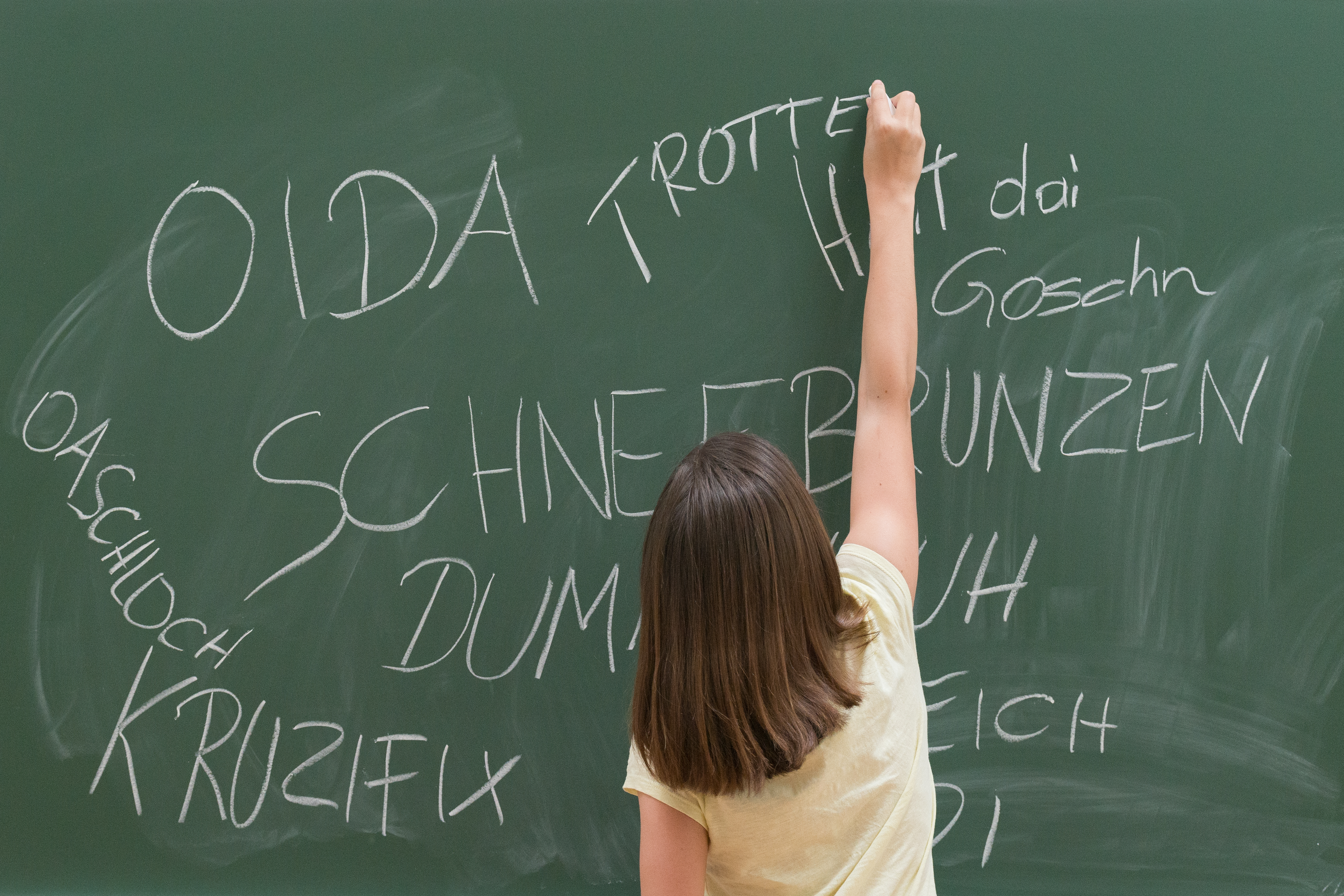 Kind schreibt Schimpfwörter auf die Schultafel