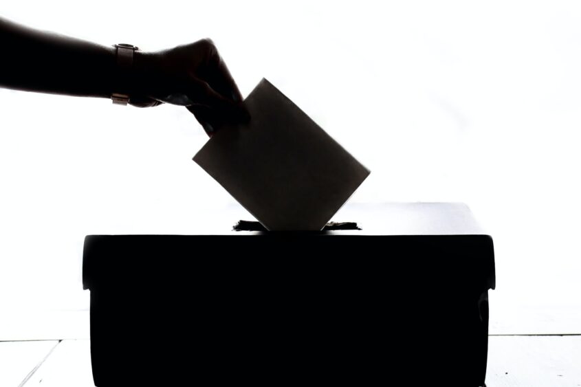 Hand wirft Wahlzettel in Urne