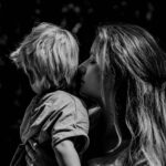 grayscale photo of woman kissing boys cheek