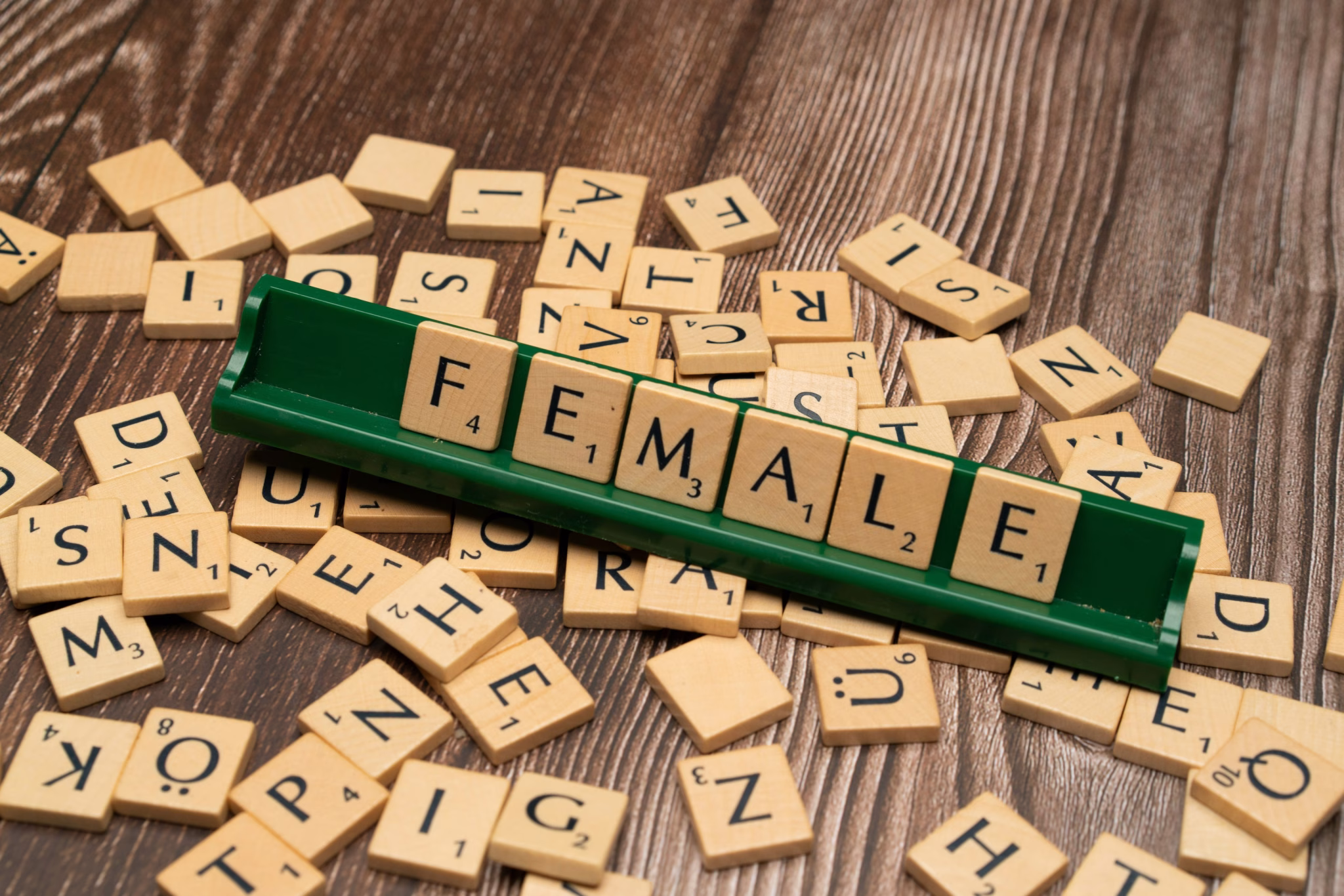 scrabble tiles spelling the word female on a wooden surface